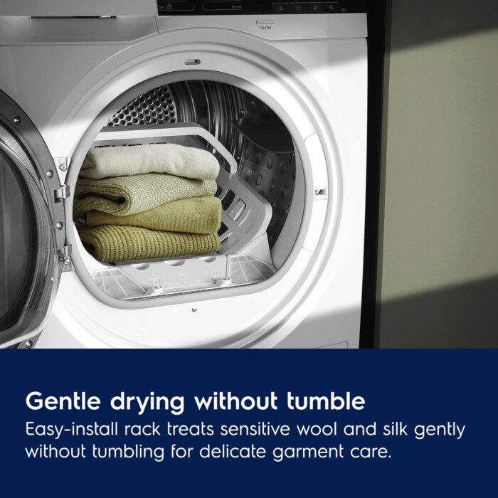 A stack of folded wool sweaters resting on a white internal drying rack inside an open Electrolux dryer drum.
