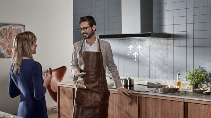 Deux personnes discutent joyeusement dans la cuisine, près d'une plaque de cuisson Electrolux et d'une hotte aspirante